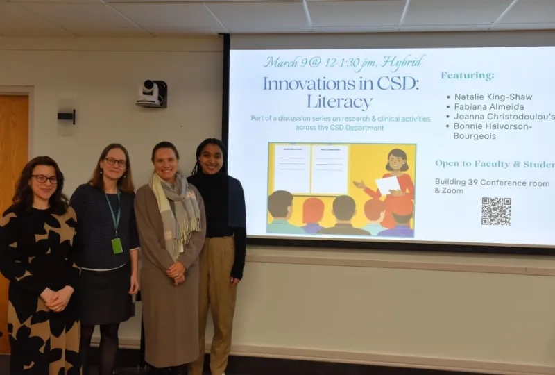 4 women standing left of a screen