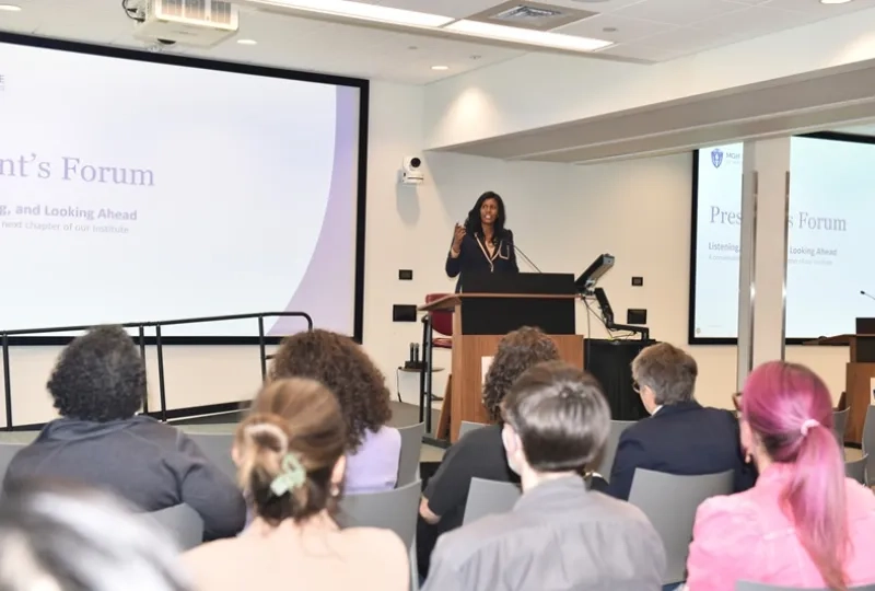IHP President Deborah Jones speaking at a podium to seated forum attendees