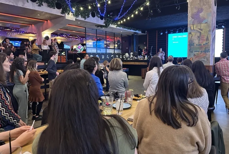 A crowd of people looks to the stage at the front of an employee event