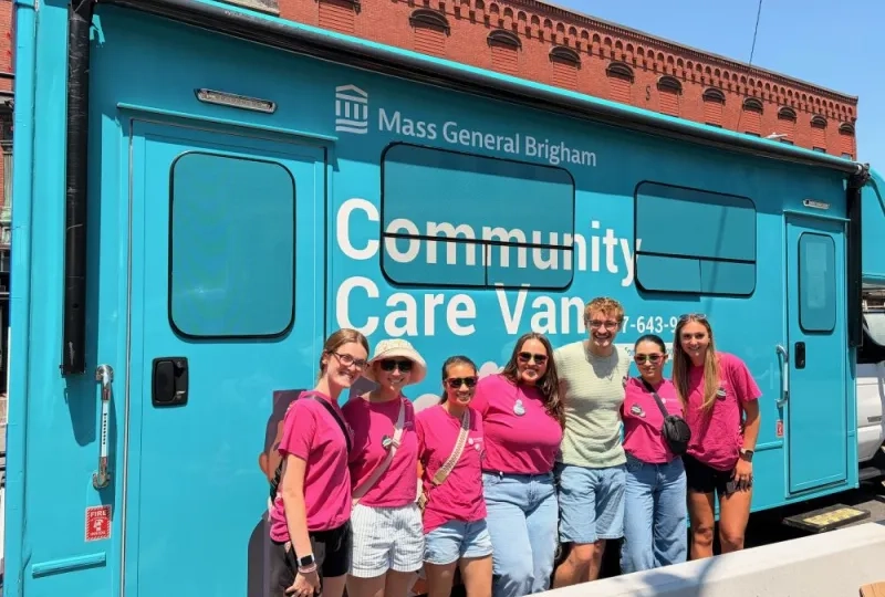 Occupational Therapy students pose in front of a community care van at a Disability Pride event in Chelsea