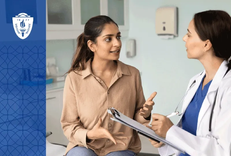 a Women's Health Nurse Practitioner in a white lab coat makes a note as a woman sitting on an exam table talks