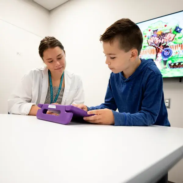 Health professional working with a child using a tablet