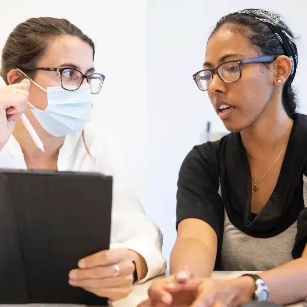 A nurse wearing a mask having a discussion with a patient