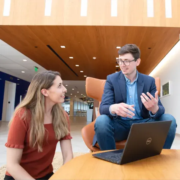 A man and a woman sitting in front of a laptop having a discussion