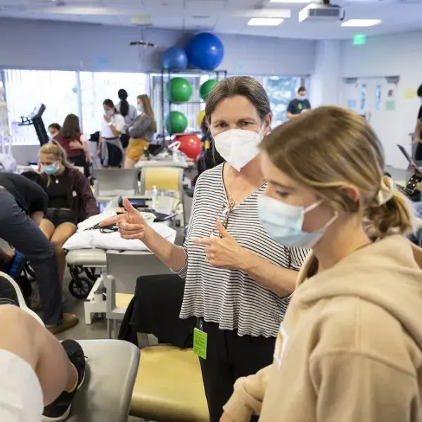 student is instructed by a faculty member in a big room where others are working