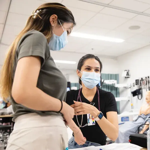 Two medical professionals wearing masks in a hospital setting