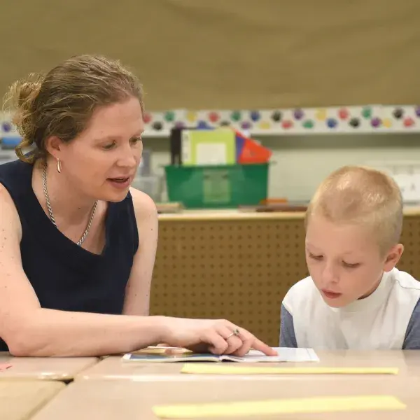 A literacy educator from the MGH IHP Literacy and Language Certificate Program working one-on-one with a student to improve reading skills. The program provides educators with advanced literacy strategies and evidence-based instruction techniques for literacy education.