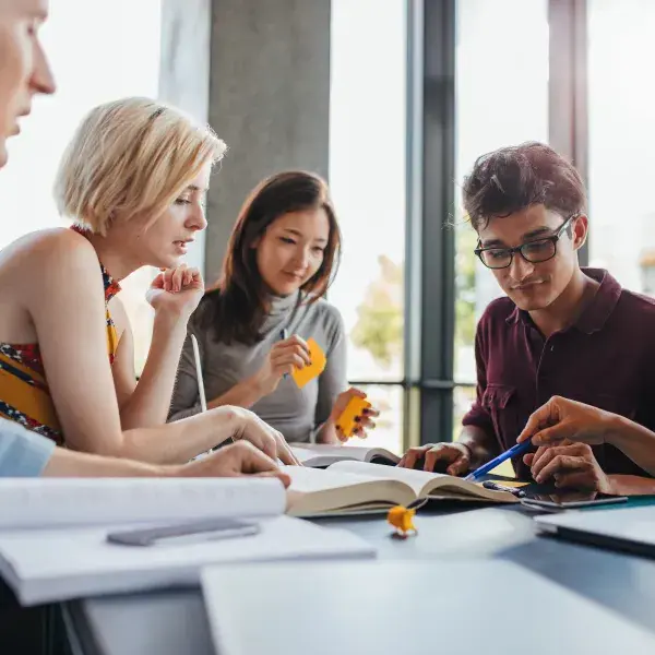 students of all types pointing at a book and using sticky notes to organize their thoughts