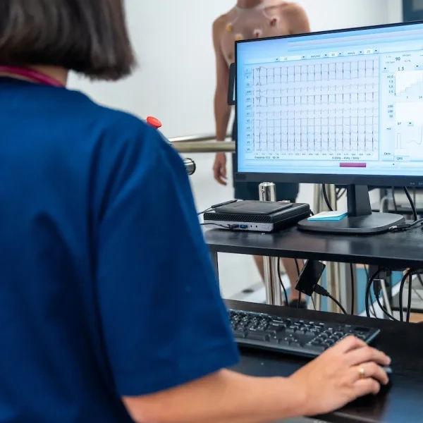 photo over the shoulder of a person in scrubs looking at data and graphs on a monitor