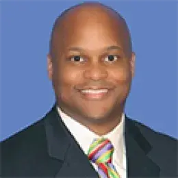 thaddeus wears a dark suit and a colorful tie