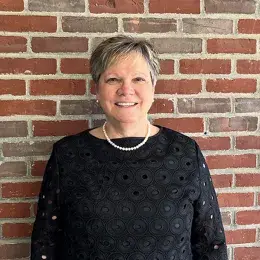 mary stands in front of a brick wall