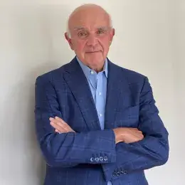 dan has grey eyebrows and wears a blue collared shirt under a dark blazer