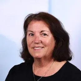 jean smiles and has shoulder length hair with a wave in it