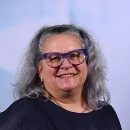 karen has purple framed glasses and wavy grey hair