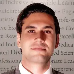 ehsan is lit from below and wears a tie and sweater over a white collared shirt