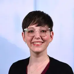 kathryn has clear framed glasses and very short brown hair