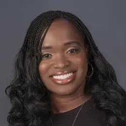 latoya has a black shirt and a silver key necklace. she wears her hair in braids.