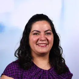 Headshot of a faculty member in the MGH IHP Doctor of Speech-Language Pathology program - she has wavy dark hair and wears a purple and black patterned top