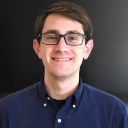 jeremy wears a navy button up and has black rectangular glasses