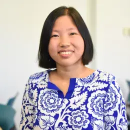 tabitha has short straight black hair and wears a cream and blue flowered top