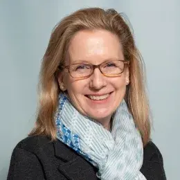 lynne wears a aqua patterned scarf and tortoiseshell glasses