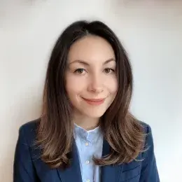 Diana Marchione has medium-length brown hair and brown eyes. She is wearing a navy blazer and light blue button up. 