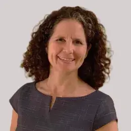 regina wears a cap sleeve navy top and has curly brown hair