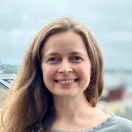 Maria Openshaw has medium length light brown hair is is wearing a grey t-shirt