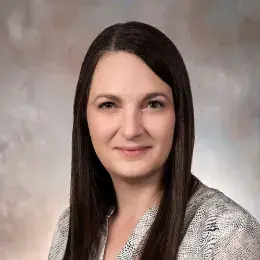 Erin Barry has long brown hair and is wearing a patterned white shirt