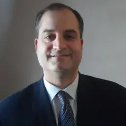 Gregory Hamann in a dark suit and white dress shirt with a striped tie.