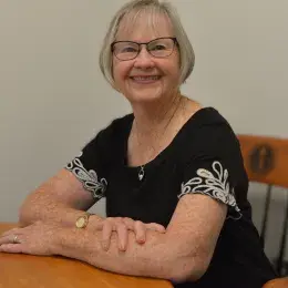 pat wears glasses and a black and white top