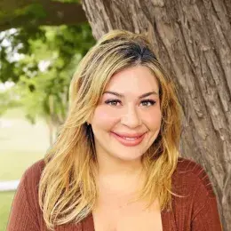 Rachel Terra Norton has medium length blonde hair and is wearing a brown shirt.