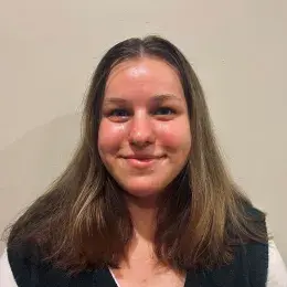 Anna Ziselman has shoulder length brown hair and is wearing a black vest