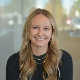 becca has a black sweater and layered gold necklaces