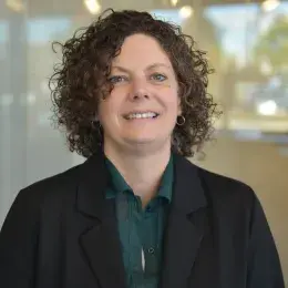 kate has curley dark brown hair and a black blazer