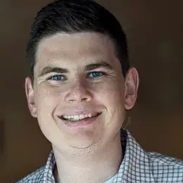 Matt O'Sullivan has short brown hair and is wearing a white and black plaid shirt