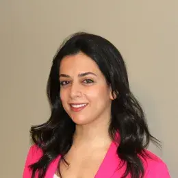 Ingrid Korbani has long black hair and is wearing a white shirt and hot pink blazer