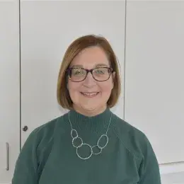 kathryn wears a moss colored top and silver looped necklace