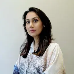 Reem Alansari has long dark brown hair and is wearing a white and blue top.