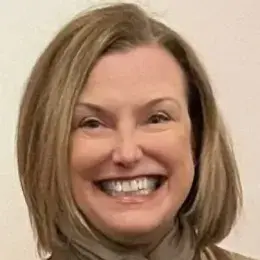 Woman with blonde hair smiling and wearing a green shirt and scarf