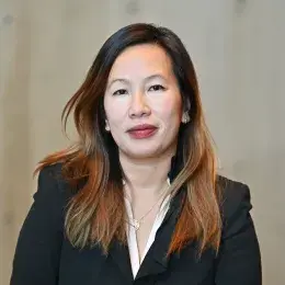 Headshot of woman with long brown hair looking at the camera and wearing a black jacket