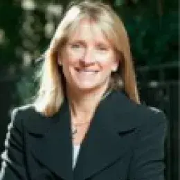 Headshot of woman with long blonde hair smiling and looking at the camera, and wearing a black jacket