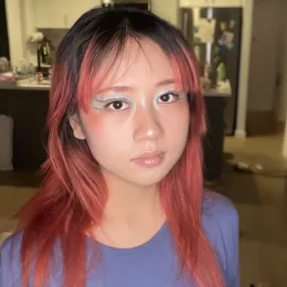 Headshot of Woman with dyed red hair wearing a blue shirt