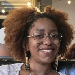 Headshot of woman with frizzy brown hair wearing glasses and long earings