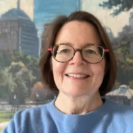 Photo of woman with dark hair wearing glasses and a blue shirt