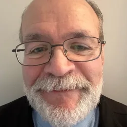 Headshot of man white white beard and mustache wearing glasses against a white background