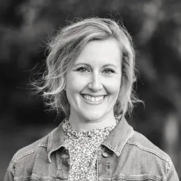 Black and white headshot of woman with shoulder length hear wearing a denim jacket