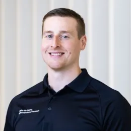 Photo of man with short hair wearing a black collared shirt in front of a white background