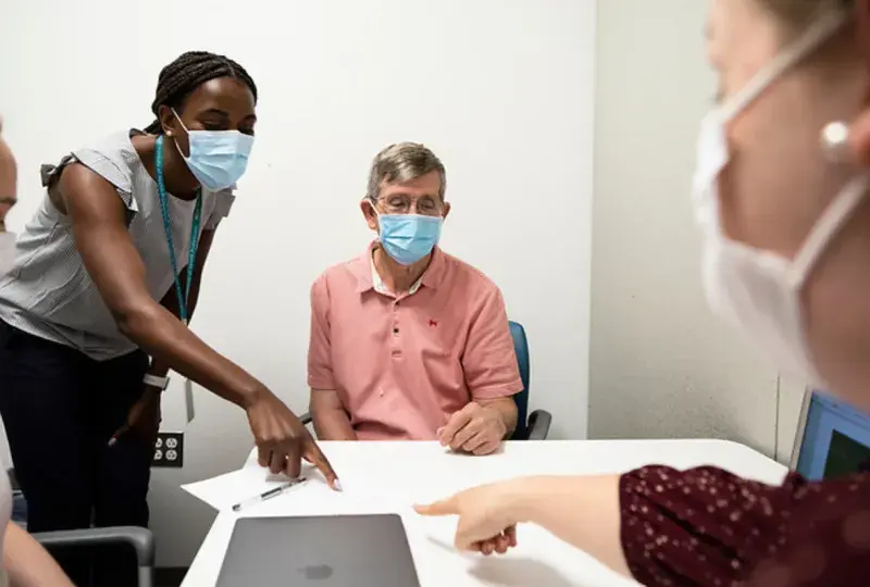 Two medical professionals pointing at a piece of paper while a patient observes 