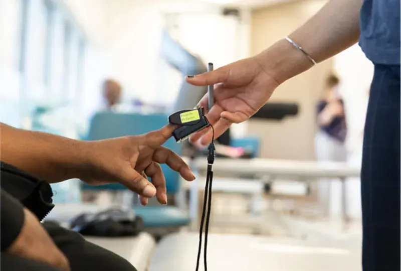 A heart and oxygen monitor being placed on the finger of a patient